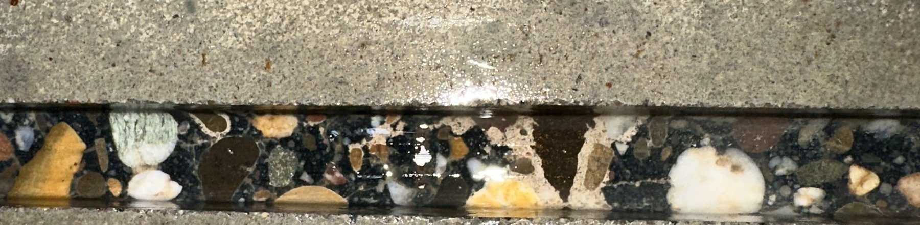 Close-up van een ingefreesde sleuf in een betonvloer met zichtbaar grind