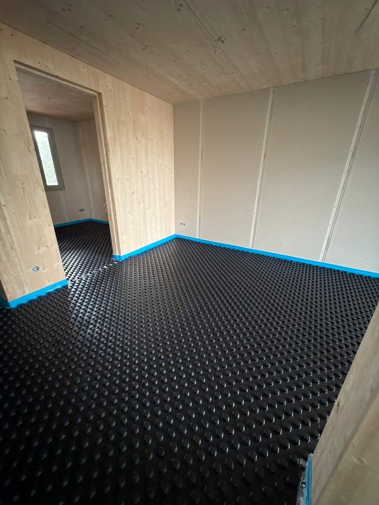 1 · Panels laid — Timber-frame home: the studded panels are down, edge insulation along every wall.