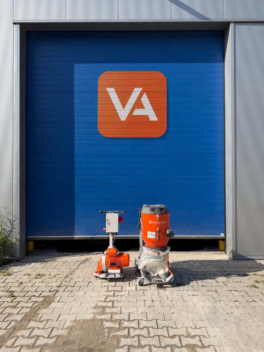 Bedrijfspand van Vloerverwarming Arnhem met het VA-logo en het machinepark