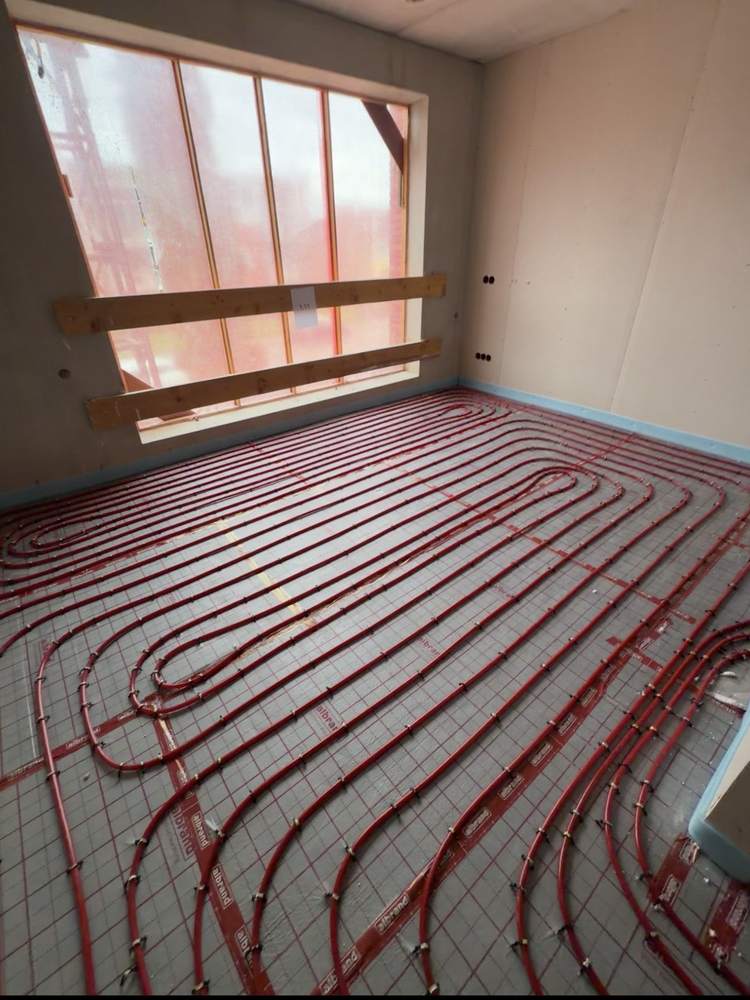 2 · Vloerverwarming getackerd — Dezelfde ruimte: de 16 mm buis met U-clips op de tackerplaat getackerd, 100 mm h.o.h. volgens het legplan.